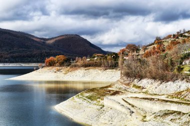 Turano Gölü çevresindeki kıyılar ve tepeler ile bulutlu bir akşam - İtalya manzara