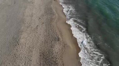 Okyanus dalgaları ve köpük ile sörf hızlı uçmak kum vurdu