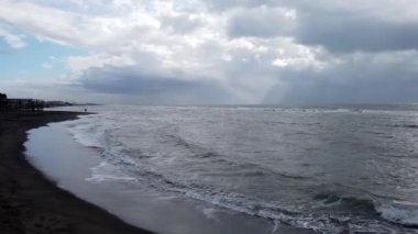 Deniz sahilde paramparça ve yalnız bir adam bulutlu bir günde kıyıya yürüyor