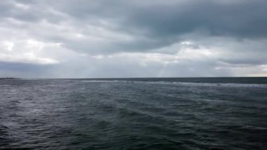 Dalgalar kadar uçuşta ağır bulutlar ve güneş ışınları ve deniz martı bulutlu ile kaba denizde fırtınası akşam