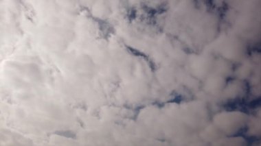 Yoğun ve sıkıştırılmış beyaz sirrokülüs bulutlarının ışık ve gölgelerle dolu mavi bir yaz gökyüzünde zaman kayması