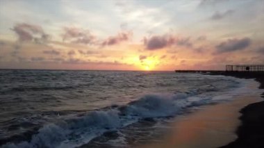 Kıyı ve gökyüzünde güzel renkli bulutlar kırma dalgaları ile, Ostia Lido Roma sahilinde sahilde günbatımı inanılmaz alacakaranlık