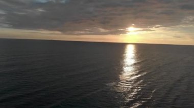 Deniz manzarası harika bir alacakaranlık ve dalgalarla dolup taşarken bir balıkçı sörf disiplini uyguluyor.