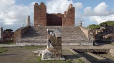 Ostia Antica'nın Roma arkeolojik kazılarında, Capitolium ile birlikte harabeler, sütunlar ve heykel ve kabartma kalıntıları ile peyzaj