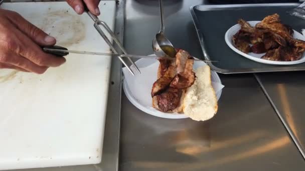 イタリアのストリートフード シェフがロースト肉とスパイシーなソースで満たされたサンドイッチを飾る — ストック動画