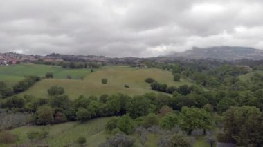 Muhteşem bir bulutlu gökyüzü ile tepeler ve ormanlar ve büyük yeşil çayırların üzerinde Italyan kırsal drone hava görünümü