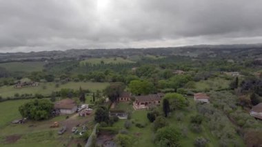 Çayırlar ve tepeler, ormanlar ve meyve ağaçları üzerinde bulutlu bir gökyüzünde Italya kırsalında uçan