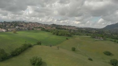 Yeşil tarım alanları ve yoğun bulutların dramatik gökyüzü ile çevrili köy silueti büyük vadiler ile hava tepelik kırsal manzara görünümü