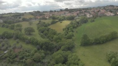 Muhteşem bir gökyüzü ve köy silueti ile tepeler arasında Meşe ormanları ve yeşil çayırlar