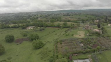 Meşe ormanları ve dramatik bir gökyüzünde tepeler ve köy silueti arasında kırsal yerleşim ile yeşil vadi ile kırsal üzerinde Manzara panoramik hava görünümü