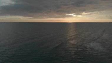 Altın saatlerinde sakin deniz ve müthiş bulutlu gökyüzü ile gün batımında okyanusun üzerinde yüksek fly