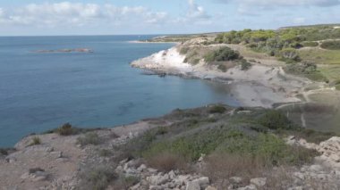Sardunya 'nın panoramik manzarası, İtalya' nın vahşi doğası. Sahil şeridi Saint Peter adasının kayalıklarından görünüyor. Mavi denizde kayalıklar ve sakin mavi sularda küçük kayalar var.
