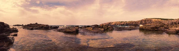 Divoký přímořský plášť za soumraku v tomto sugestivním 180 stupňovém Ponorné panorama s skalními útvary vytesanými větrem a čistým mořem — Stock fotografie