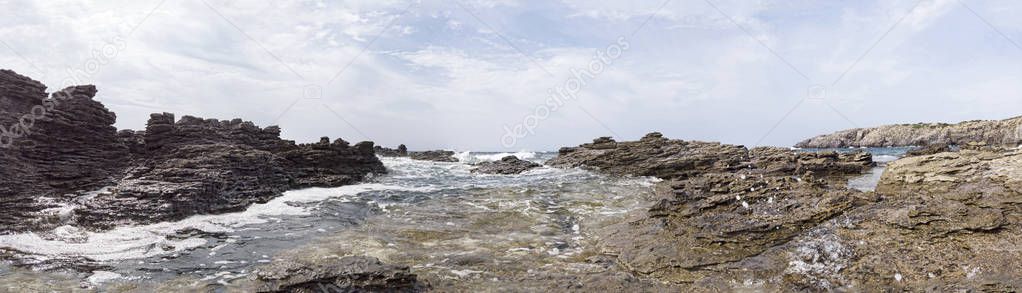 The rough seas breaks on the rocks sculpted by the wind forming a scenic landscape