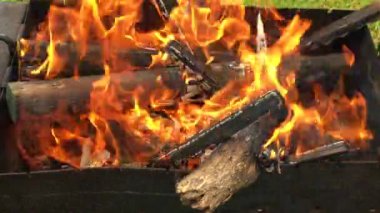Dilimlenmiş tahtadan çıkan güzel kırmızı ateş, metal brazier 'ın içinde koyu gri siyah kömür. Parlak sarı ateşte, brazier 'da odun yanıyor. Alevler barbekü pişirmeye hazırlanıyor. Brazier doğa bbq üzerine.