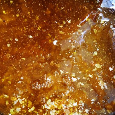 Altın nektarla doldurulmuş altıgen bal peteklerinden bir damla bal damlıyor. Bal peteği yaz kompozisyonu. Doğal bal damlası, balmumu çerçeveli arı damlası. Bal damlası bal damlatıyor bal peteğine.