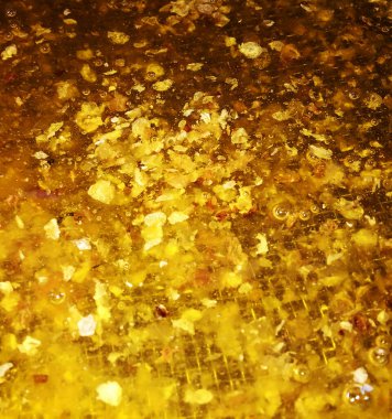 Altın nektarla doldurulmuş altıgen bal peteklerinden bir damla bal damlıyor. Bal peteği yaz kompozisyonu. Doğal bal damlası, balmumu çerçeveli arı damlası. Bal damlası bal damlatıyor bal peteğine.