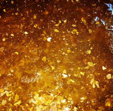 Altın nektarla doldurulmuş altıgen bal peteklerinden bir damla bal damlıyor. Bal peteği yaz kompozisyonu. Doğal bal damlası, balmumu çerçeveli arı damlası. Bal damlası bal damlatıyor bal peteğine.