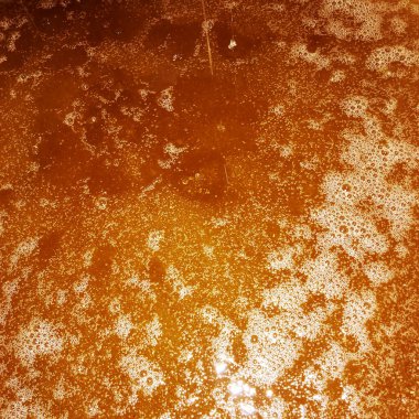 Altın nektarla doldurulmuş altıgen bal peteklerinden bir damla bal damlıyor. Bal peteği yaz kompozisyonu. Doğal bal damlası, balmumu çerçeveli arı damlası. Bal damlası bal damlatıyor bal peteğine.