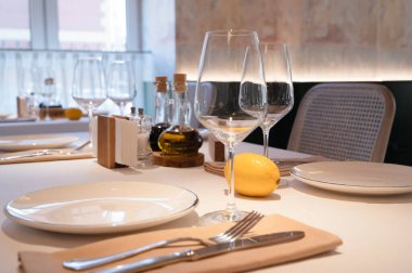 Şık yemek masası düzenlemeleri zarif cam eşyalar, bir şişe zeytinyağı ve taze limon dilimi sergiliyor.