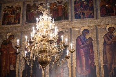 Göz kamaştırıcı bir avize, süslü bir kilisede canlı dini simgelerin üzerinde ışıldıyor.