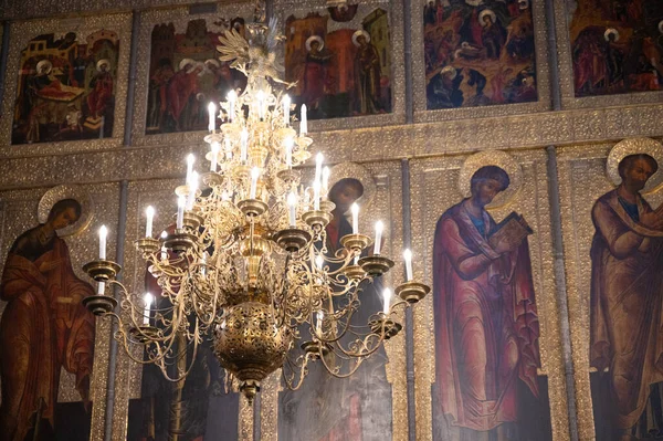 Göz kamaştırıcı bir avize, süslü bir kilisede canlı dini simgelerin üzerinde ışıldıyor.