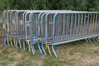 A large collection of metal barriers has been carefully stacked on top of each other in an organized manner, ready for use