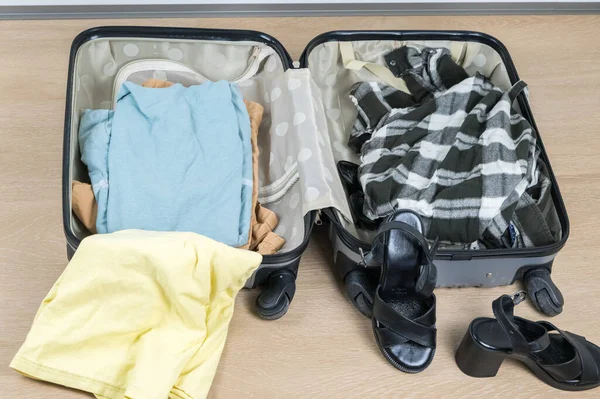 A travel suitcase packed with an assortment of clothing items and various shoes, all ready for an exciting trip