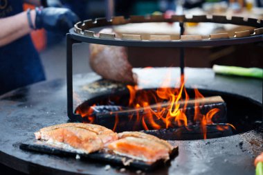 Arka planda alevler olan ızgara ızgarada ızgara et ve somon pişiyor. Barbekü partisi ve yemek konsepti için mükemmel..