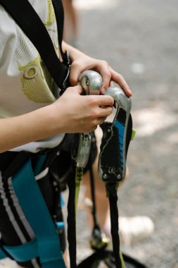 Yükselen güvenlik ekipmanlarını birbirine bağlayan bir çocuğun yakın çekim görüntüsü. Emniyet kemeri, halat ve karabina, güvenlik, bağımsızlık ve öğrenmeyi temsil eden detaylı bir çekim..