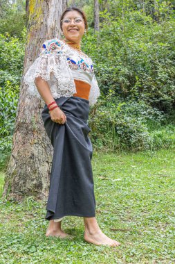 Otavalo, Ekvador: 6 Ağustos 2025: Yerli Otavalo 'lu kadın çimenlerde çıplak ayakla yürüyor, geleneksel giysiler içinde.