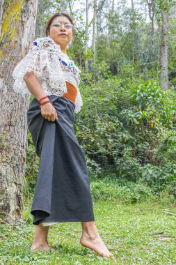 Otavalo, Ekvador: 6 Ağustos 2025: Yerli Otavalo 'lu kadın çimenlerde çıplak ayakla yürüyor, geleneksel giysiler içinde.