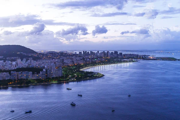 Deniz ve bulutlu gökyüzü ile şehrin üzerinde dramatik günbatımı