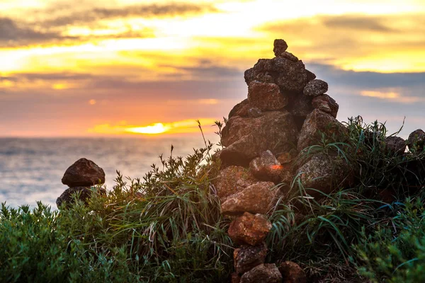 Ground view of sunset at seashore with stones and green grass