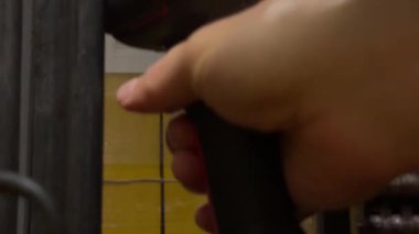 Yoğun bir depoda, bir işçi stok seviyelerini verimli bir şekilde yönetmek için el cihazıyla nesneleri tarar. Makinelerin sesi öğleden sonra vardiyasında çalışkan atmosferi güçlendirir..