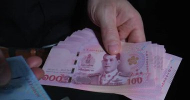 Birileri gece canlı bir pazarda Tayland bahtı değiş tokuşu yapıyor, renkli banknotlar sergiliyor ve satıcılar ve müşteriler olarak bölgenin hayat dolu atmosferini gösteriyor..