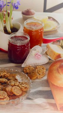 Bu sette çeşitli ev yapımı kurabiyeler, renkli reçeller ve güzel bir masada sergilenen taze ekmek yer alıyor. Çiçekler davetkar atmosfere sıcak bir dokunuş ekler..