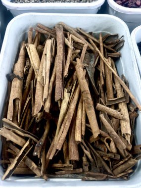 Tarçın çubukları beyaz plastik bir kabın içine yerleştirilmiş. Yemeklerde kullanılan baharatlar. Yiyecek malzemeleri..