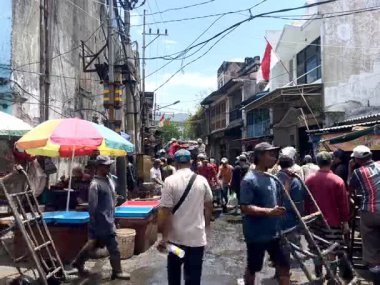 Surabaya, Endonezya - 22 Eylül 2025: Geleneksel bir pazarda faaliyet gösteren taze çiğ balık satıcıları. Tedarikçiler fıçılarca taze balığı boşaltıp yüklüyorlar. Yerel gıda kültürü ve yerel ekonominin yakalanması.