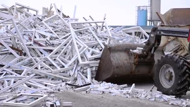 Бульдозерный трактор перемещает отходы от производства пластиковых окон на свалку — стоковое видео