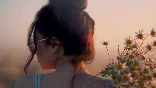 Seorang gadis cantik mengenakan gaun dan kacamata merah muda membawa bunga aster di bahunya — Stok Video