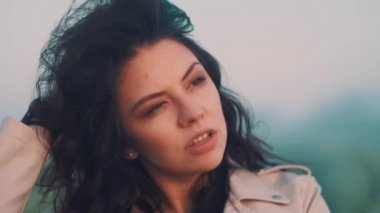 Elma saati olan bir kız ellerini saçlarının arasından geçirir ve onlarla oynar.
