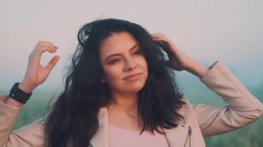 Elma saati olan bir kız ellerini saçlarının arasından geçirir ve onlarla oynar.