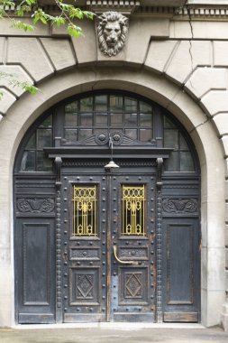 Antik sahte kapılar binanın cephesinde. Çınar ağacı ön planda yeşil yaprakları