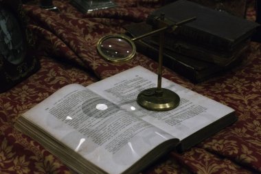 Vintage Büyüteç yakın çekim vintage öğeler arasındaki bir kitap bir tablo üzerinde bir altın desenli kırmızı bir masa örtüsü yukarıda