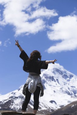 Kadın gezgin, Gürcistan 'daki Kazbek Dağı' nın zirvesinin keyfini çıkarıyor. Dağlarda yürüyüş, kızlar için aktif yaşam tarzı.