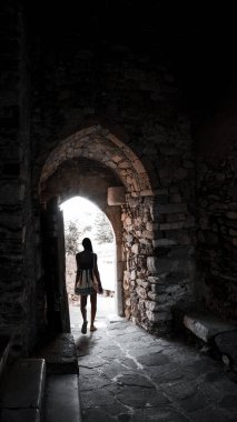 Kız Yunan adalarının antik manzarasına tek başına seyahat ediyor. Tüneli olan kemerli bir cadde. Kemerdeki çıkışta, koyu tenli genç ve çekici bir kadın.