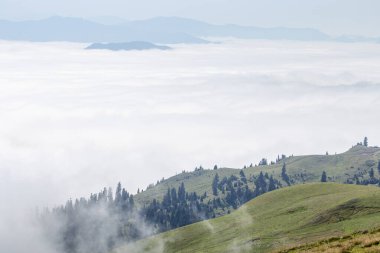 Yuvarlanan yeşil tepeleri dağınık kulübeleri ve dolambaçlı yolları olan nefes kesici bir dağ manzarası. Sis ve bulutlar vadiyi örterek doğanın dokunulmamış güzelliğinin huzurlu ve huzurlu bir görüntüsünü yaratıyor.