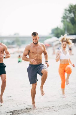 Grup Genç çekici insanlar plajda eğlenmek ve bazı fitness egzersiz yapıyor.