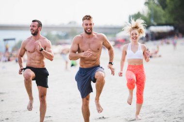 Grup Genç çekici insanlar plajda eğlenmek ve bazı fitness egzersiz yapıyor.